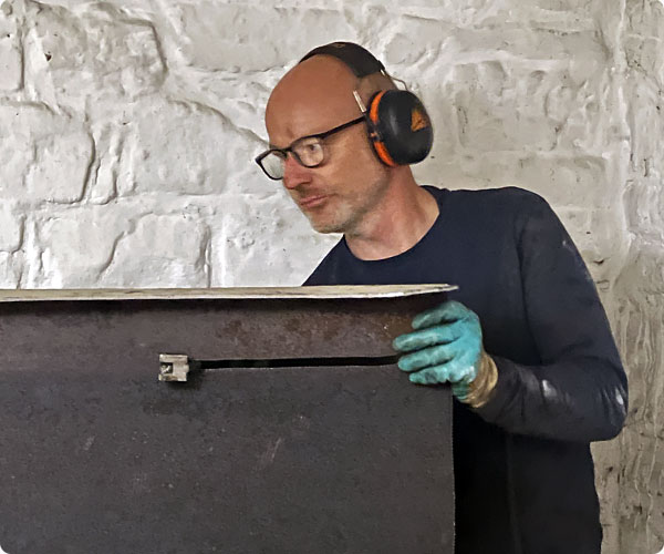 Geoffrey De Leye pendant le découpage d'une cuve à mazout en métal